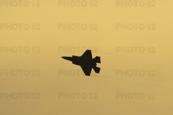 Lockheed Martin F-35 Lightning II fighter military aircraft of the United States air force USAF silhouette in flight at sunset at RAF Lakenheath airbase, Suffolk, England, United Kingdom