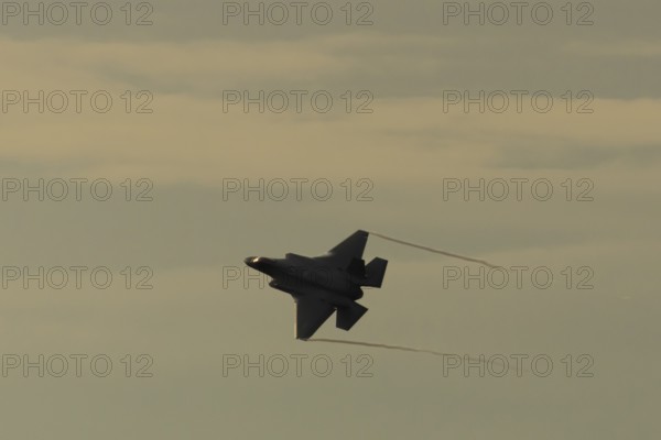 Lockheed Martin F-35 Lightning II fighter military aircraft of the United States air force USAF silhouette in flight at sunset at RAF Lakenheath airbase, Suffolk, England, United Kingdom