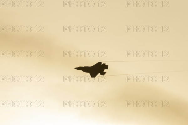 Lockheed Martin F-35 Lightning II fighter military aircraft of the United States air force USAF silhouette in flight at sunset at RAF Lakenheath airbase, Suffolk, England, United Kingdom
