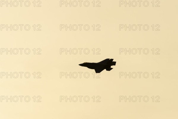 Lockheed Martin F-35 Lightning II fighter military aircraft of the United States air force USAF silhouette in flight at sunset at RAF Lakenheath airbase, Suffolk, England, United Kingdom
