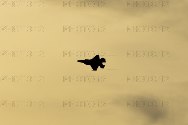 Lockheed Martin F-35 Lightning II fighter military aircraft of the United States air force USAF silhouette in flight at sunset at RAF Lakenheath airbase, Suffolk, England, United Kingdom