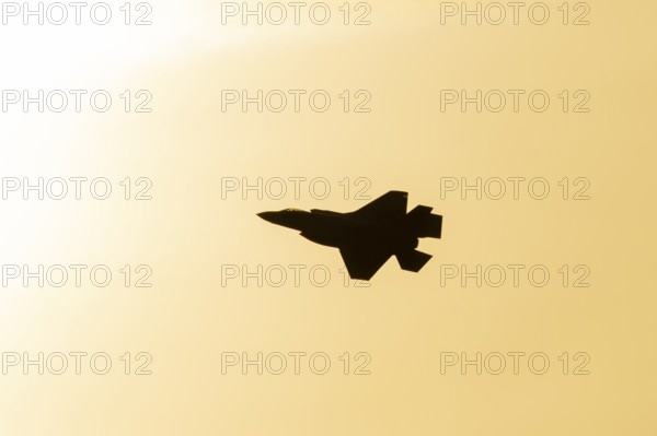 Lockheed Martin F-35 Lightning II fighter military aircraft of the United States air force USAF silhouette in flight at sunset at RAF Lakenheath airbase, Suffolk, England, United Kingdom