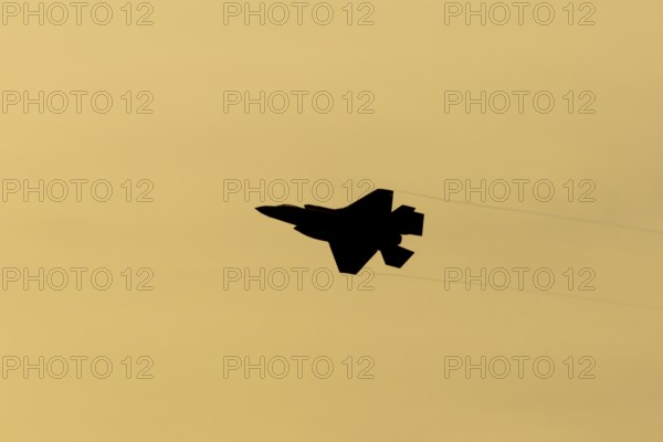 Lockheed Martin F-35 Lightning II fighter military aircraft of the United States air force USAF silhouette in flight at sunset at RAF Lakenheath airbase, Suffolk, England, United Kingdom