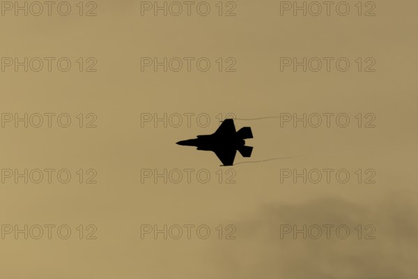 Lockheed Martin F-35 Lightning II fighter military aircraft of the United States air force USAF silhouette in flight at sunset at RAF Lakenheath airbase, Suffolk, England, United Kingdom