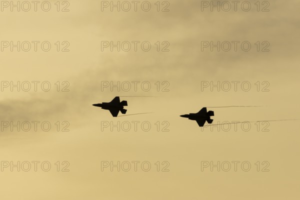 Lockheed Martin F-35 Lightning II fighter two military aircraft of the United States air force USAF silhouette in flight at sunset at RAF Lakenheath airbase, Suffolk, England, United Kingdom