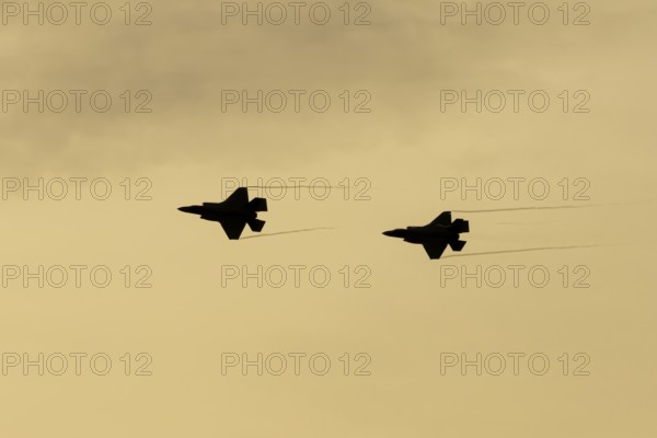 Lockheed Martin F-35 Lightning II fighter two military aircraft of the United States air force USAF silhouette in flight at sunset at RAF Lakenheath airbase, Suffolk, England, United Kingdom