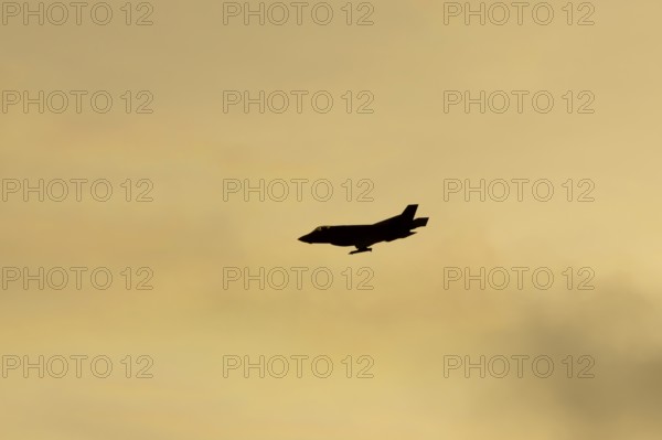 Lockheed Martin F-35 Lightning II fighter military aircraft of the United States air force USAF silhouette in flight at sunset at RAF Lakenheath airbase, Suffolk, England, United Kingdom