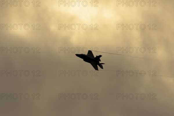 Lockheed Martin F-35 Lightning II fighter military aircraft of the United States air force USAF silhouette in flight at sunset at RAF Lakenheath airbase, Suffolk, England, United Kingdom