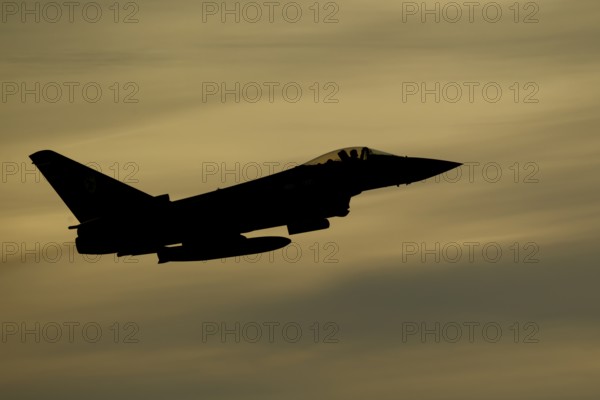 Eurofighter Typhoon silhouette of a military fighter jet aircraft of the Royal air force RAF flying at sunset, England, United Kingdom