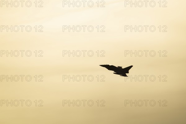 Eurofighter Typhoon silhouette of a military fighter jet aircraft of the Royal air force RAF flying at sunset, England, United Kingdom
