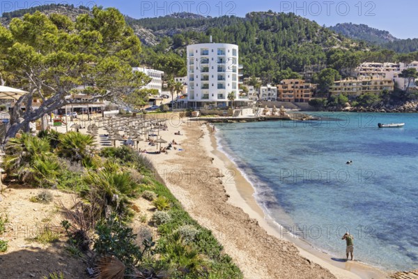 Scenics view at a coast village at the Mediterranean Sea with a sand beach and hotels by the sea at a resort a sunny summer day, Sant Elm, Mallorca, Spain