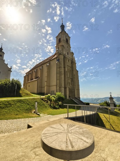 Baroque church in the sunshine with an impressive tower, surrounded by green landscape and blue sky, Pöllau Styria Austria
