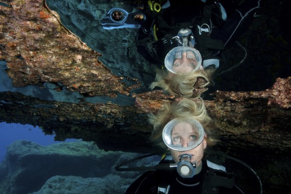 Diver with open blonde hair reflected in large air bubble in cave ceiling in underwater grotto, East Atlantic, Tenerife, Canary Islands, Spain