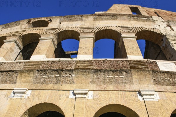 Steep view upwards to partially restored façade Exterior façade with large arched windows Brick arches of ancient Roman Colosseum from antiquity, Rome, Lazio, Italy