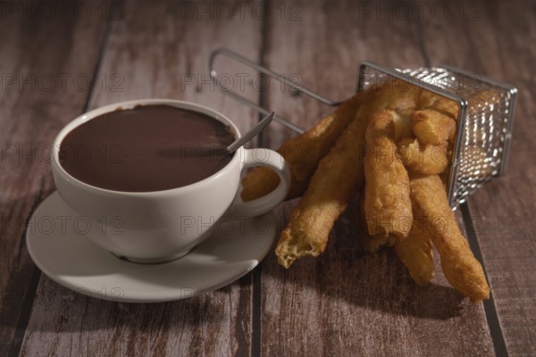 Cup of hot chocolate with freshly made churros on wooden background typical spanish breakfast on holidays