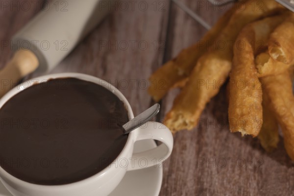 Cup of hot chocolate with freshly made churros on wooden background typical spanish breakfast on holidays