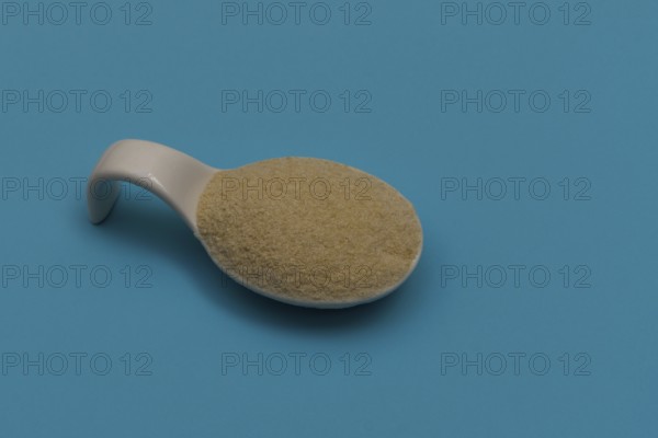 White ceramic spoon with breadcrumbs and blue background