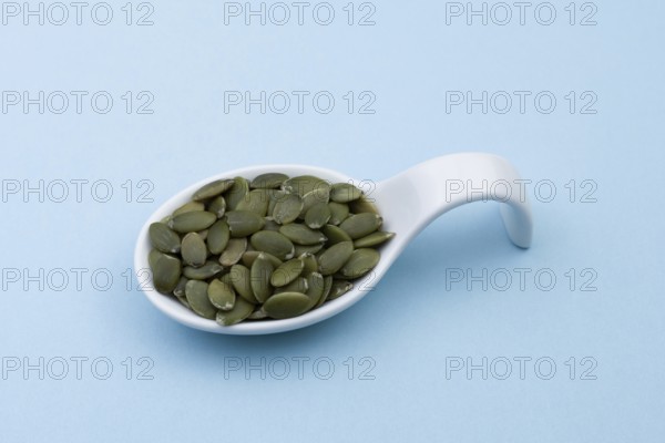 White ceramic spoon with pumpkin seeds and blue bottom