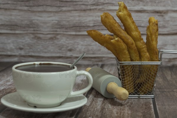 Cup of hot chocolate with freshly made churros on wooden background typical spanish breakfast on holidays
