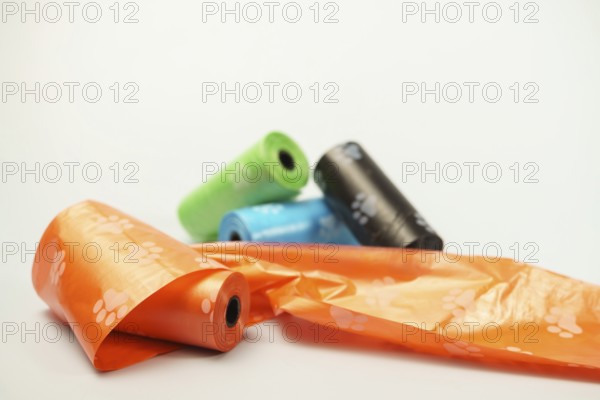 Rolls of biodegradable dog poop bags with paw print pattern unrolling on a white background