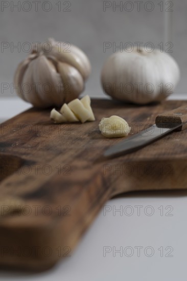 Whole and peeled garlic on wooden board and white background