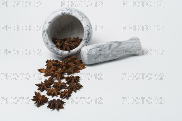 Close-up of star anise illicium verum in a white dish with a marble mortar isolated on white background and copy space