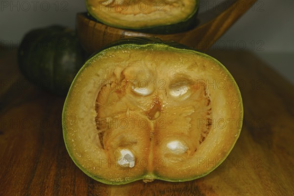 Green pumpkins cut in half on wood and white background