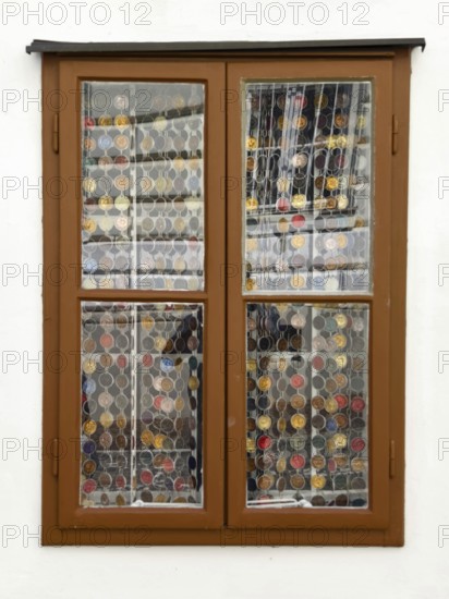 Window with decorative coin collection behind glass, framed by a simple wooden structure Mödling Lower Austria Austria