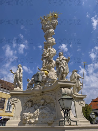Baroque fountain with artistic sculptures under a slightly cloudy, blue sky Mödling Lower Austria Austria