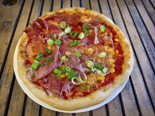 Pizza with ham and spring onions served on a table. Hearty and fresh with an Italian flavour Home-cooked Lower Austria Austria