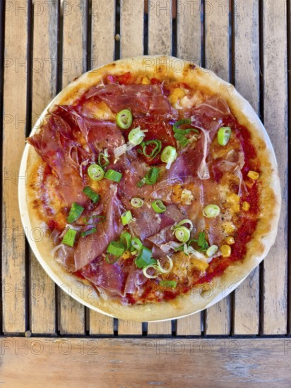 Pizza with ham, spring onions and cheese served on a wooden base. Italian flavours with fresh ingredients Home-cooked Lower Austria Austria