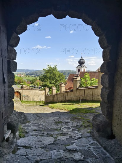 View through a stone Tor tor to a historic church and a landscape under a cloudy sky Riegersburg Styria Austria