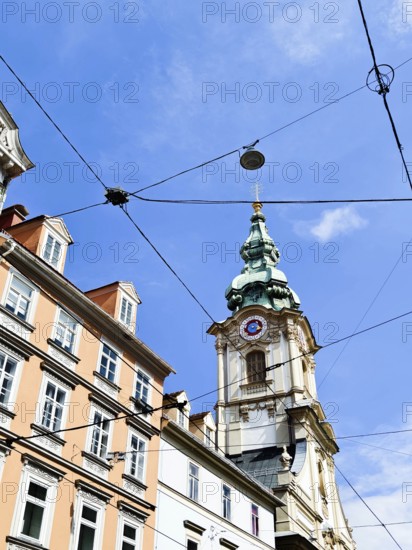 Detailed church tower rises above bourgeois buildings with a clear sky Herz Jesu Kirche Graz Styria Austria