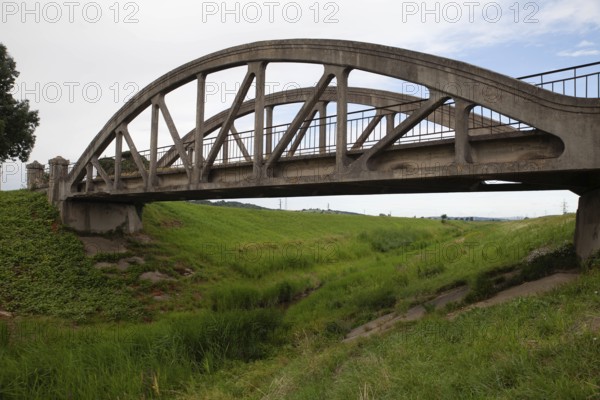 A concrete arch of the bridge stretches across a green meadow under a clear sky Perschling Flood Channel Bridge Lower Austria Austria