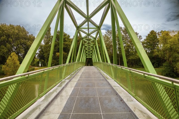 A modern, green metal bridge with a lattice design that leads into a forest Traisenbrücke Lower Austria Austria