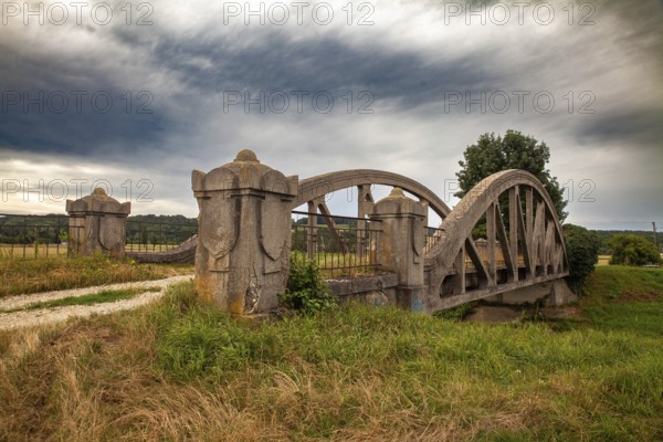 A stone bridge with dramatic clouds in the background, embedded in a rural landscape Perschling flood channel bridge Lower Austria Austria