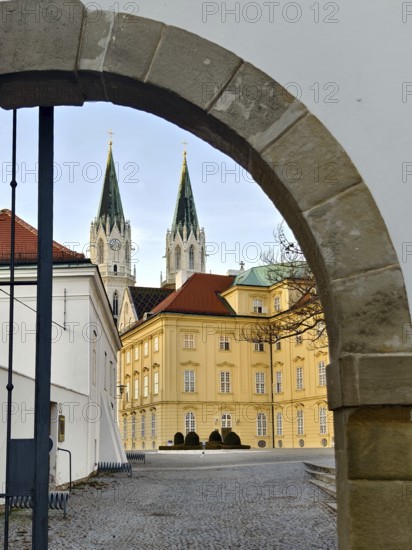 View through a stone gate onto a baroque building with two Gothic church towers, Klosterneuburg Lower Austria Austria