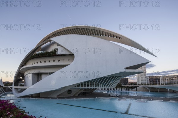 Building with curved white design next to a turquoise-coloured pool under the evening sky Opera