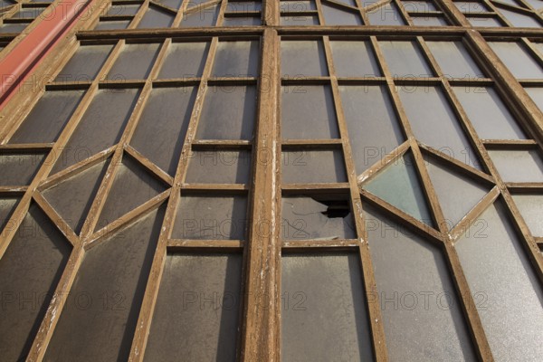 A window with broken glass and a complex metal structure