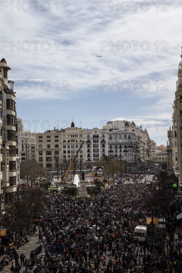 Large crowd in a city in front of tall buildings and a slightly cloudy sky MascletÃ¡ de Fallas
