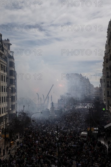 Dense crowds in the city with rising smoke and buildings MascletÃ¡ de Fallas