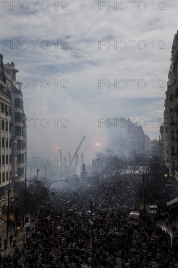 Tightly packed crowd under clouds of smoke on a city street Mascletá de Fallas