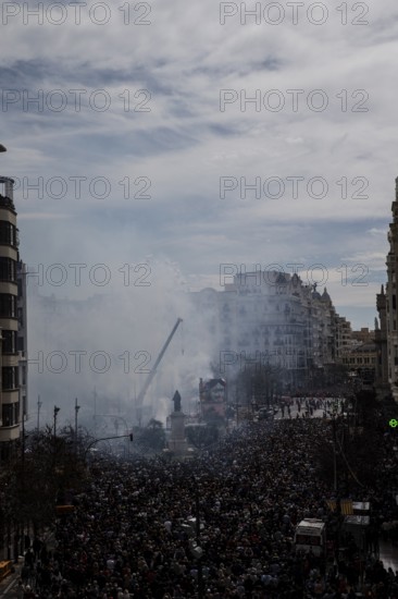 Celebration in the city with a dense crowd and smoke in the air MascletÃ¡ de Fallas