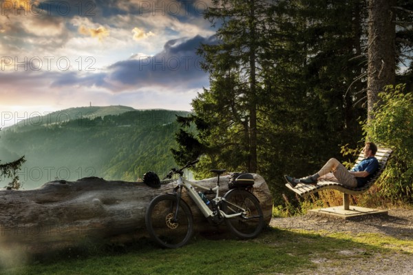 Cyclist enjoying the view from a bench on the Feldberg, Menzenschwand, Black Forest, Baden-Württemberg, Germany