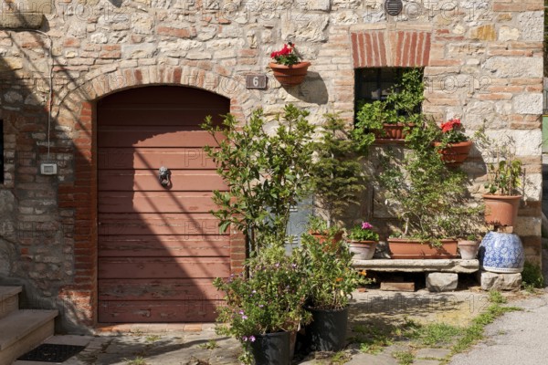 Tuscany country house detail with flower bench planter next to old wooden door quarry stone wall, Tuscany, Italy