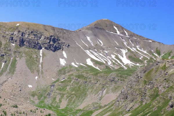 View to the rear eroded steep rocky slope mountainside slope with gravel rock thawing snow remains top right hilltop above 2802 metres high alpine road Cime de la Bonette, Mercantour National Park, Jausiers, Departement Alpes-de-Haute-Provence, France