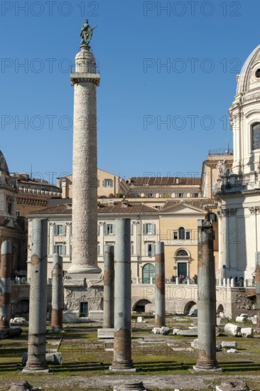 View of part of historic Trajan's Forum with ancient column fragments from Basilica Ulpia in front, behind it 40 metre high column of honour Victory Column from the year 113 made of Carrara marble from Lunensian marble for Roman Emperor Trajan from antiquity, at the top statue of Apostle Peter Saint Peter, Saint Peter, erected in 1587 at the behest of Pope Sixtus V, below small platform with railing, Rome, Lazio, Italy