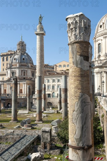 View of part of historic Trajan's Forum with ancient column fragments in front, behind it 40 metre high column of honour Victory Column from the year 113 made of Carrara marble from Lunensian marble for Roman Emperor Trajan from antiquity, at the top statue of St. Peter the Apostle erected in 1587 at the behest of Pope Sixtus V, St. Peter the Apostle, St. Peter the Saint, below small platform with railing, in the background church of Santa Maria di Loreto, Rome, Lazio, Italy
