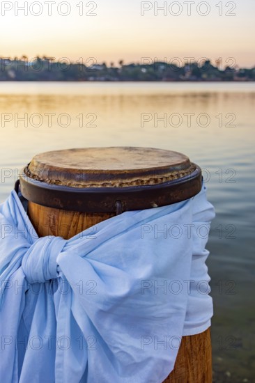 Decorated atabaque in front of the water during sunset, Pampulha lagoon, Belo Horizonte, Minas Gerais, Brazil