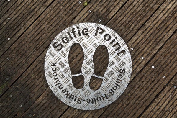 Selfie point, metal plate, shoe prints on a plank path at the source of the River Ems near Schloss Holte-Stukenbrock, Senne nature reserve, North Rhine-Westphalia, Germany